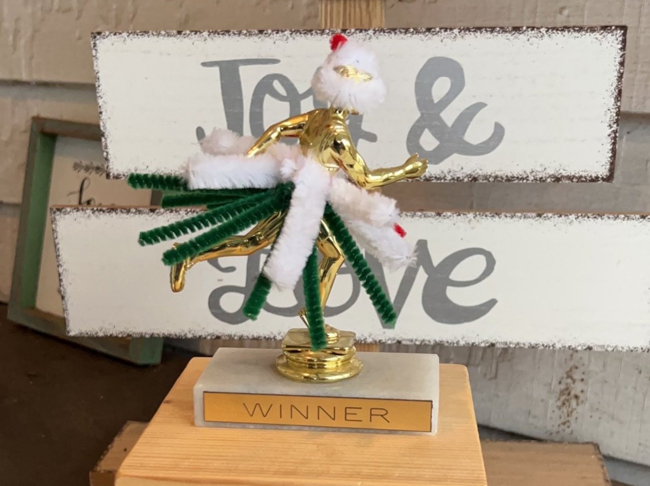 A gold-colored plastic trophy is dressed in a festive costume of pipe cleaners.