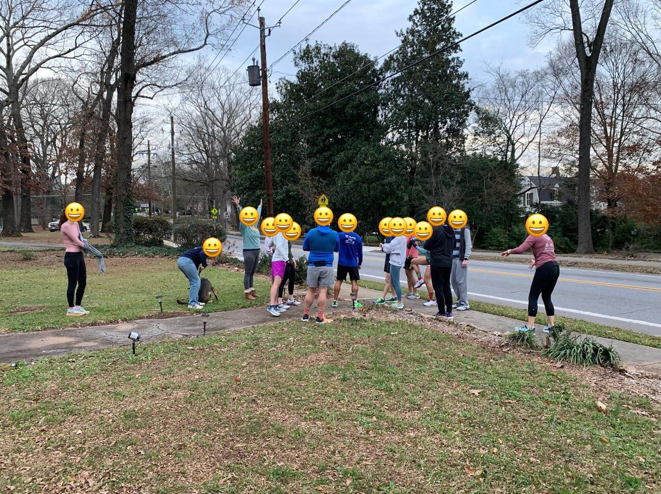 A group of about 20 people assemble outside on the sidewalk for the start of a race.