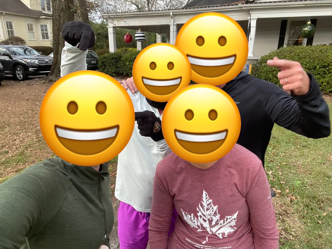 4 people pose for a picture. 2 are pointing to the woman in front.