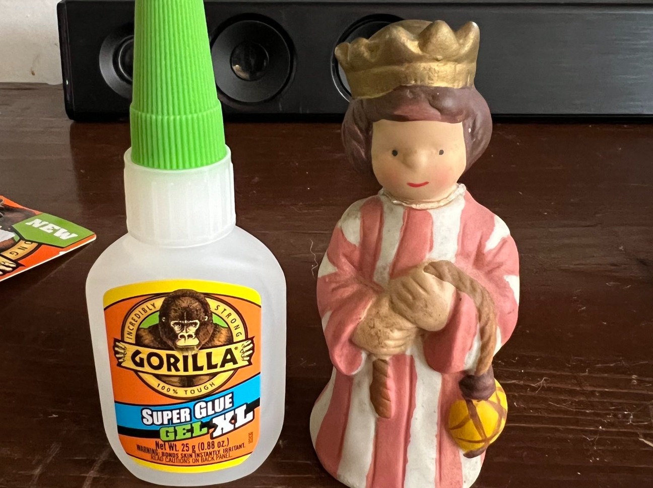 A figurine sits on a table next to a small bottle of Gorilla Glue.